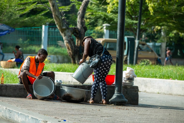 Food vendors wash pots and pans on November 17, 2022 at a square in front of the Pantheon, Haiti’s National Museum, in Champ de Mars. Photo by Marvens Compère for The Haitian Times