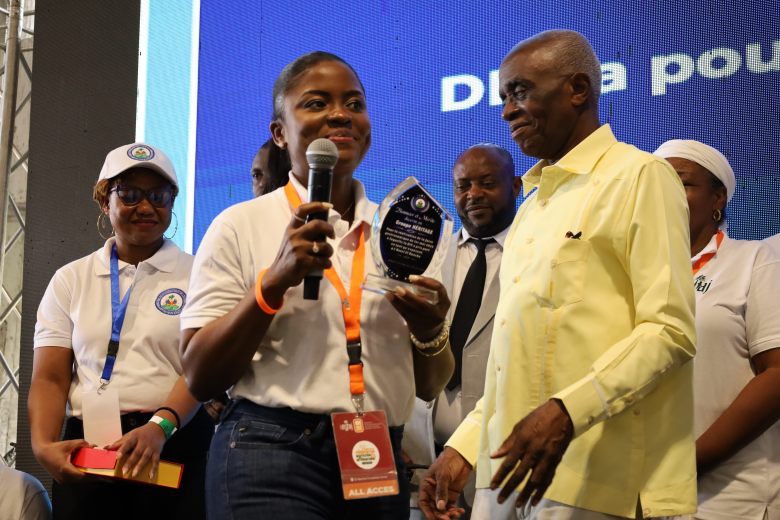 Gwoup Eritaj President Géraldine Padovanive Scown receives an honorary plaque from Minister of the Interior and Local Authorities Ardon Bien-Aimé at the first Agricultural and Artisanal Resistance Fair in Pétion-Ville, Port-au-Prince, on May 1, 2025. Photo by Dieugo André for The Haitian Times.