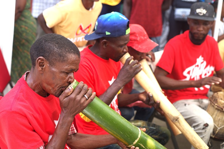 A musician plays a horn made of bamboo during a performance at Institut Sacré-Cœur du Cap-Haïtien on May 1, 2025. Photo by Onz Chéry / The Haitian Times.