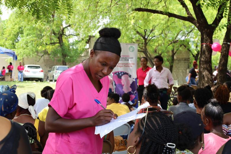A midwife registers the women’s names to create their files, enabling them to be called for medical consultations during the mobile clinic organized by the Haitian Midwives Association (ASFH) at the Quiskeya Chapel in Delmas 75 on Saturday, May 3, 2025. Photo by Dieugo André for The Haitian Times.