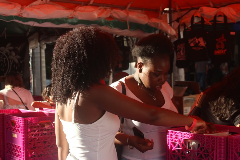 Young visitors look through vinyl records at a vendor tent during the Street Fair at the Miami Book Fair on Sunday, Nov. 23, 2025. Photo by Béatrice Vallières for The Haitian Times.