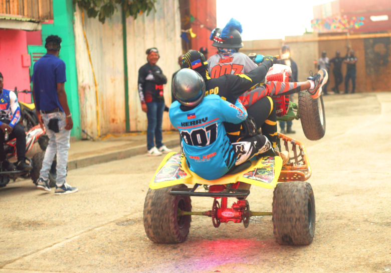 A rider performs a wheelie with two passengers during the third edition of the Ruff Ryders Block Party in Cap-Haïtien on March 7, 2026. Photo by Onz Chéry / The Haitian Times.