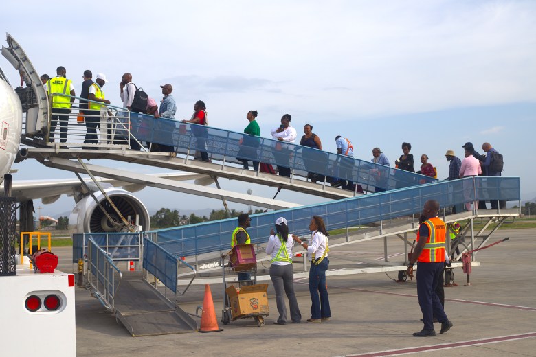 Carry-ons and gift bags in hand, passengers board the aircraft. Photo by Onz Chéry/The Haitian Times.