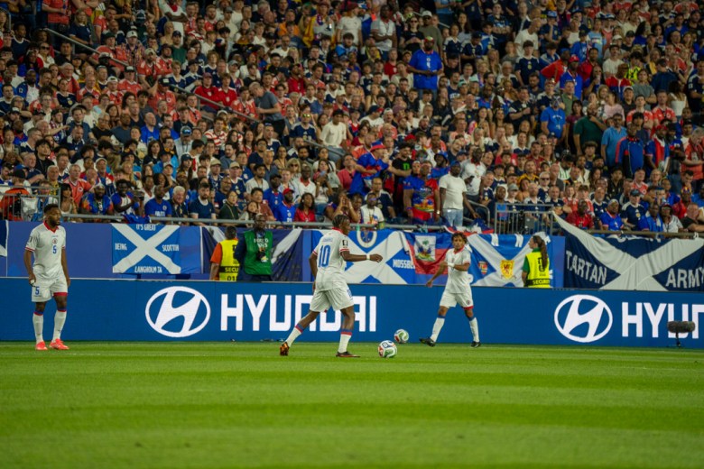 As Grenadier Jean-Richer Bellegarde moves across the field, he passes at least four Scottish banners with slogans such as “It’s great to be Scottish” and one Haitian flag on display. Photo by Fredner Cayemitte/The Haitian Times
